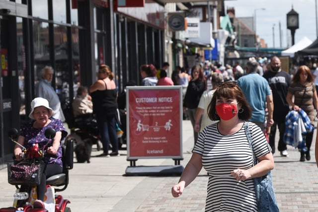 On a busy, sunny Saturday many shoppers hit the high street wearing a mask.