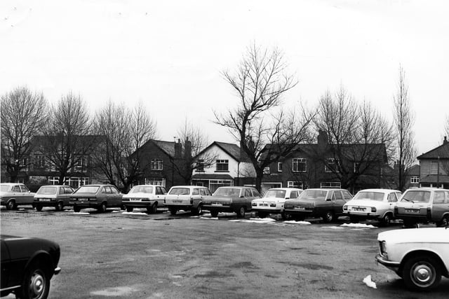 Old Lane looking from a car park towards housing across the road in February 1980. Semi-detached and detached houses can be seen.