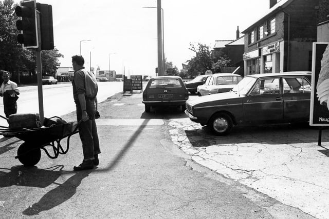 Dewsbury Road at the junction with Old Lane (foreground) in June 1980. A workman with a wheelbarrow of tools is seen and work on the road is in progress.