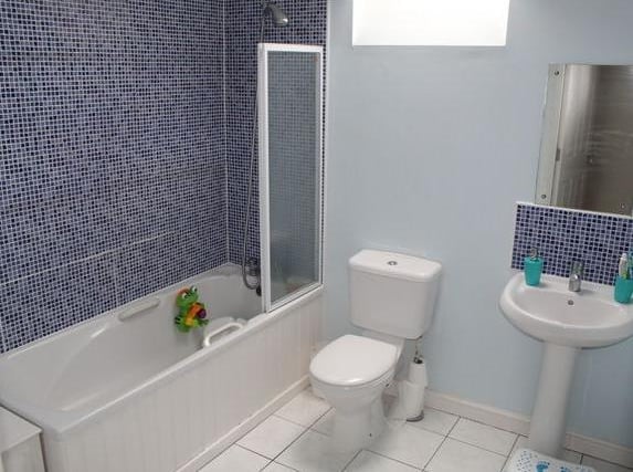 With a tiled floor and tiled splashback, this generous bathroom has a white three piece suite comprising; bath with shower over & shower screen, low flush w.c. and Wash hand basin with mixer tap.