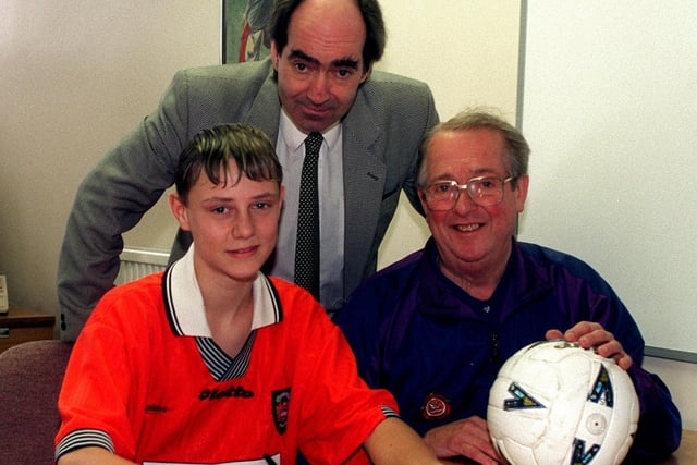 Southlands High School pupil Simon Grand signs for Blackpool FC watched by Blackpool chief youth scout, Fred O'Donoghue, right, and deputy head Brian Souter.