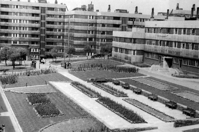 This undated photo shows gardens laid out in front of the Savile Restaurant. Benches are provided for residents. Trees and shrubs soften the appearance of the flats.