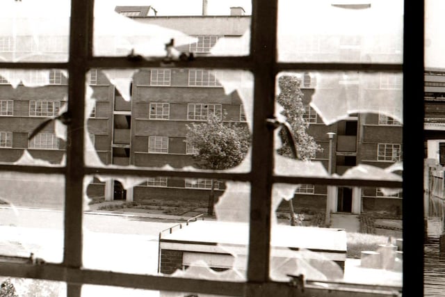 A view looking through a broken window in one block of Quarry Hill Flats,possibly Moynihan House, towards another block (York House). The flats were in the process of demolition at the time.