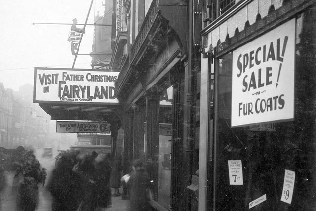 Hitchen's department store showing sign advertising 'Father Christmas in Fairyland'. A mechanical bell-boy is at the bottom of a ladder going up the front of the building.
