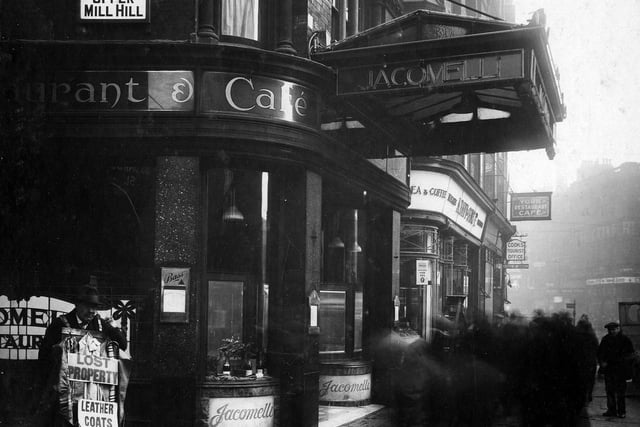 Corner of Boar Lane and Upper Mill Hill, showing Jacomelli's cafe. On the left is a lost property man carrying leather coats etc. Further along are York Restaurant, Cook's Tourist Office, Arthur Davy and Son, Provisioners.