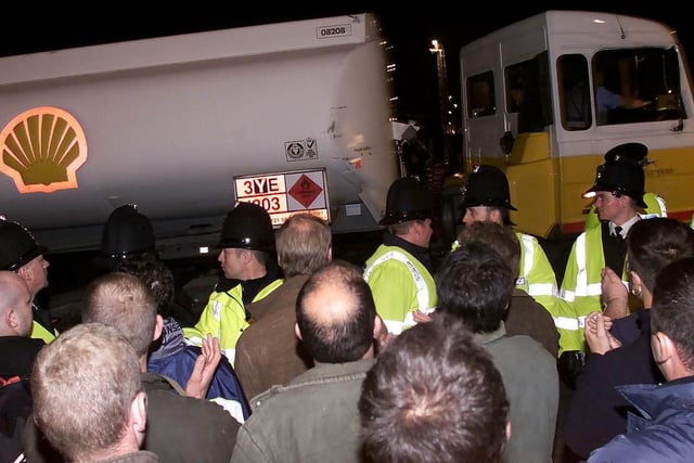 Police officers form a human barricade to keep protesters from eight tankers which left the Stanlow Oil refinery carrying fuel for essential services