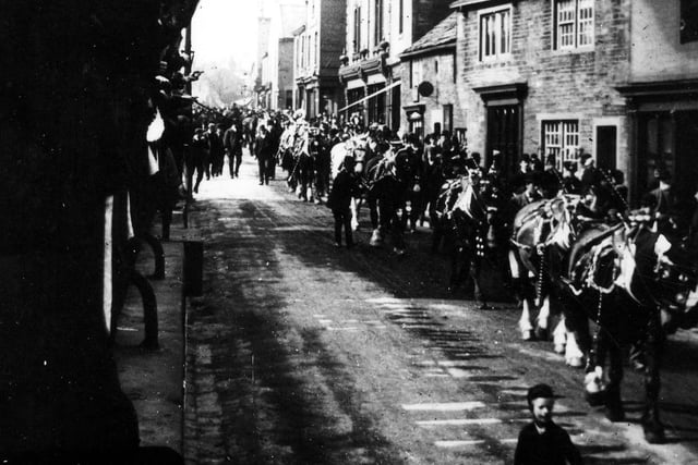 Decorated horses are led along Town Street as part of a procession also including horse-drawn vehicles and floats. Year unknown.
