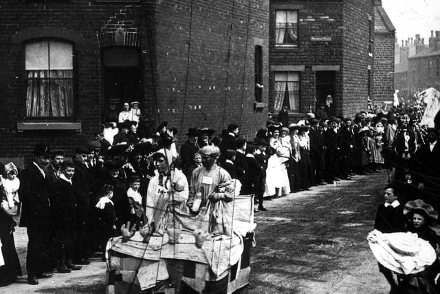 Crowds line the streets of Bramley to watch the Carnival procession go past. The parade is travelling along Elder Road by the junctions with Bramley Terrace (left) and Bramley Place. Year unknown.