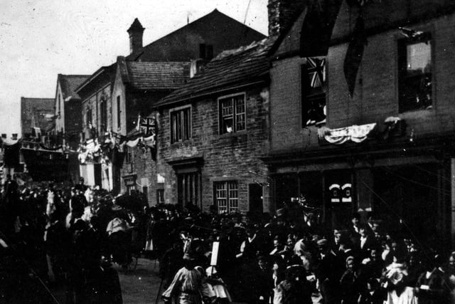 Crowds lined along Town Street watching the Bramley Carnival procession go past. The street is decorated for the Carnival
