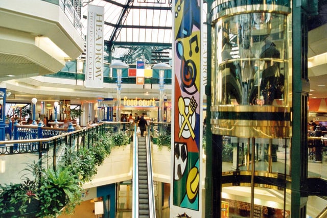 View of glass lift and escalator leading to the food court on the top level of The Headrow Shopping Centre in October 1999.