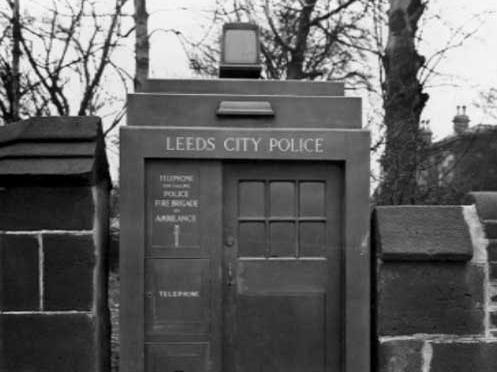 March 1935. Close up of police telephone box on Headingley Lane. It is set into a stone wall. The words Leeds City Police are above the door.