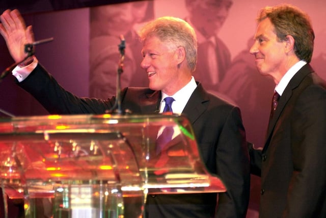 Former US President Bill Clinton waves as Labour Prime Minister Tony Blair looks on in Blackpool, in October 2002