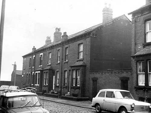 A row of four back-to-back terraced houses on Oldfield Terrace each with a small private garden in December 1972. On the right is a shared outside toilet block.