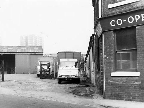 This view looks from the bottom of Copley Hill onto Back Wellington Row in September 1971. A large warehouse is visible to the left with two delivery vehicles belonging to Simon's Fruit, parked in the road.