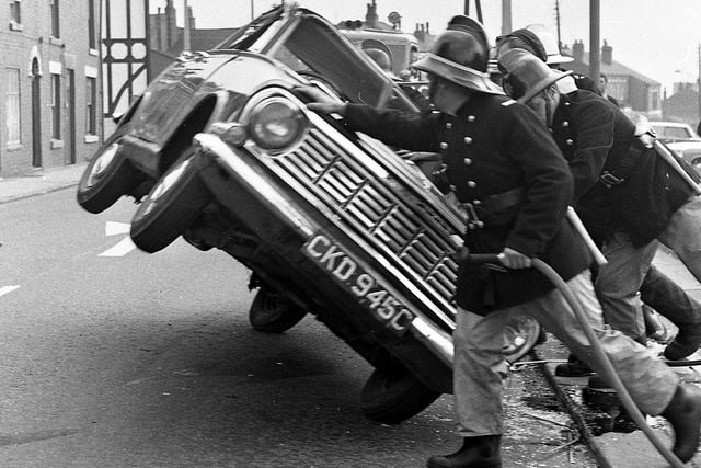 An overturned car in Whelley is dealt with by Wigan's firefighters in 1972