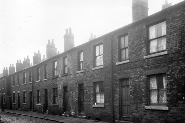 A row of back-to-back terraced houses on soon to be demolished Dow Place in February 1959 with a ginnel allowing access to the shared outside toilets and Moor Crescent Road.