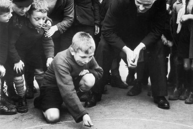 Pupils of Whitwood Mere School in Castleford watching a fellow pupil competing in a game of marbles. The winner represented the school in an inter-school match on Shrove Tuesday.