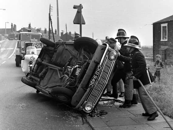 An overturned car in Whelley is dealt with by Wigan's firefighters in 1972