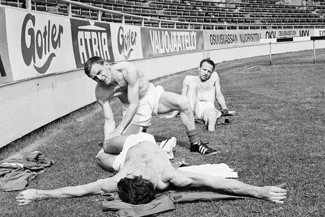 13th July 1966: Nobby Stiles watches a trainer help Peter Bonetti perform a few warm-up exercises during the England team's pre-World Cup tour