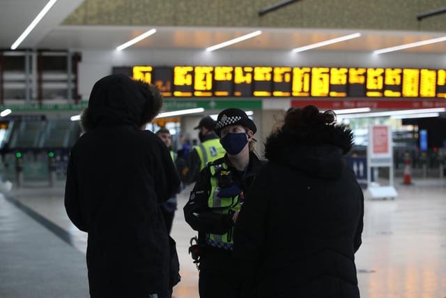 A police officer speaking to passengers to see where they are going at Leeds train station at the start of a four week national lockdown for England.