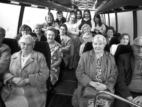 A group of pensioners from Ince on board a coach for a day trip with younger volunteers in 1974.