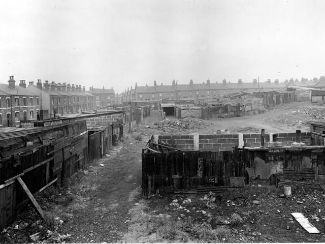 A view shows general disorder at an allotment on Clark Lane in July 1951. Dirt tracks run past various wood and brick built structures. Houses on Temple View are visible on the left.
