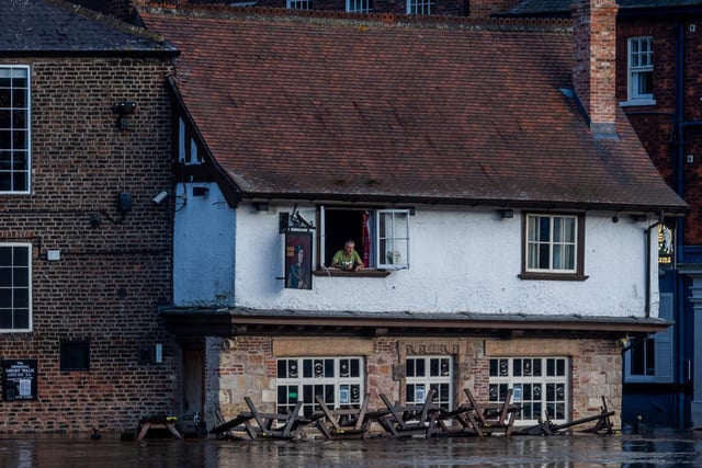 Colin Fidler, landlord of the Kings Arms, King's Staith, York, peers from his window as floodwater from the River Ouse is pumped out of his pub.