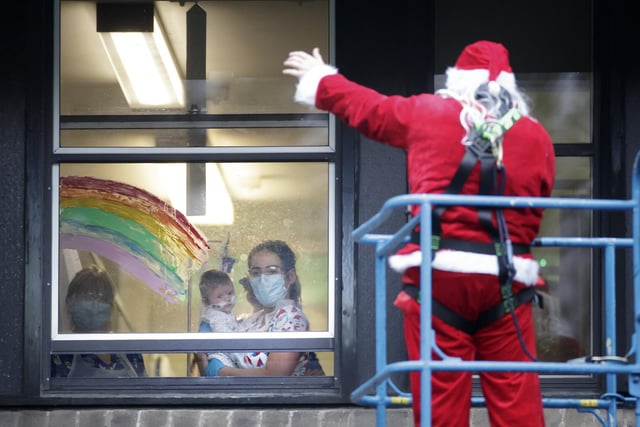 Father Christmas waves to a baby at Leeds Children's Hospital from a platform with Santa visits off-limits due to the Covid-19 pandemic