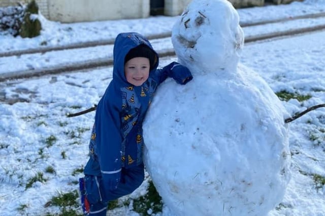 Four-year-old Charlie Ingham is thrilled with the snowman he built in Manchester Road, Burnley