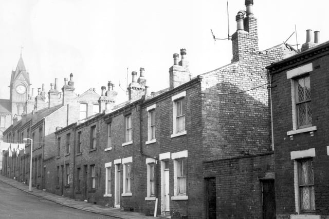 November 1969 and pictured is Bolland Street. Four double fronted back-to-back terraced houses are flanked by two yards of shared outside toilets. In the distance on the left a clock tower is visible on Cross Quarry Street.