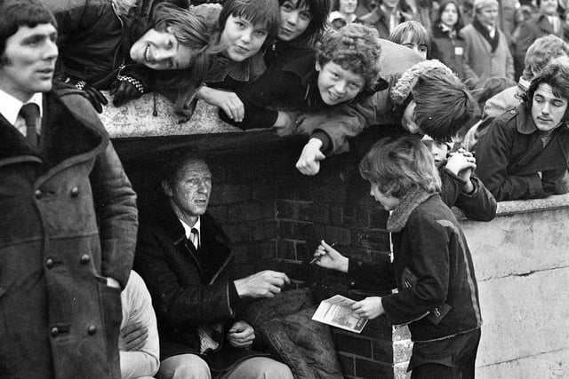 Sheffield Wednesday manager Jack Charlton signs autographs in the dugout before his Division 3 team took on Wigan Athletic in the FA Cup 2nd round match at Springfield Park on Saturday 17th of December 1977. 

Latics won the game 1-0 with a goal from Maurice Whittle.