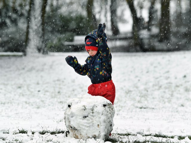 Three-year-old Winston Hallas builds a snowman in Pudsey Park