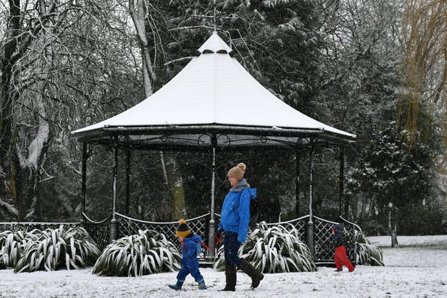 Kim Berley and her son Alfie, 2, walk past the bandstand in the snow at Pudsey Park