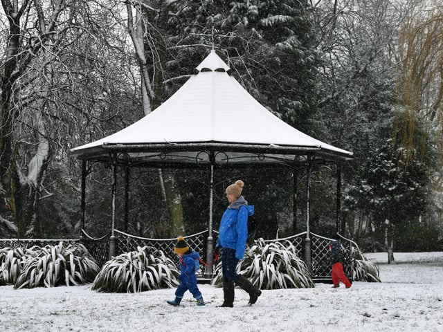 Kim Berley and her son Alfie, 2, walk past the bandstand in the snow at Pudsey Park