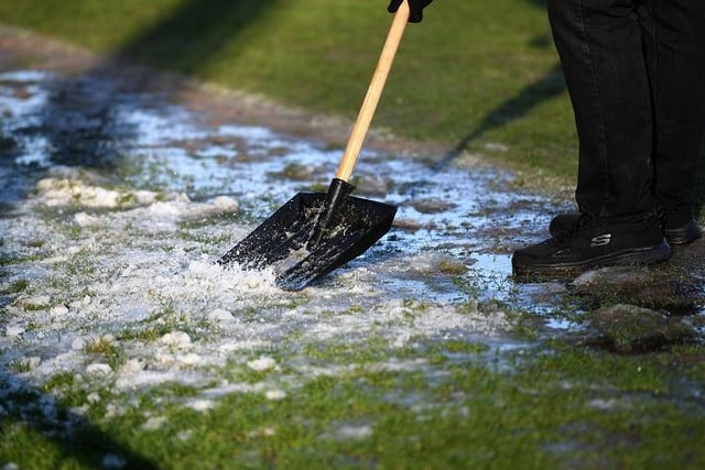 Groundsmen clear the pitch of snow before the Emirates FA Cup third round match at Victory Park, Chorley