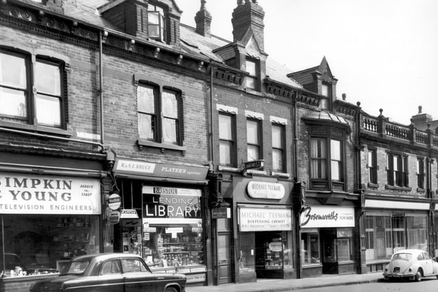 June 1965. Shops in view include Simpkin and Young, radio and television engineers and R & S.E. Bruce's confectioners and tobacconists. Jars of sweets line the shop windows. This shop was also a private lending library. Next is a chemists then Bosomworth's furnishers.