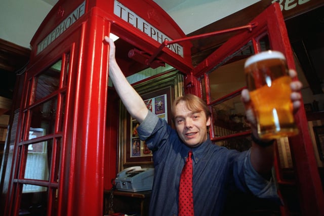 Tim Worthington, the manager of the Red Lion pub in Longton near Preston in the red phonebox inside the pub.