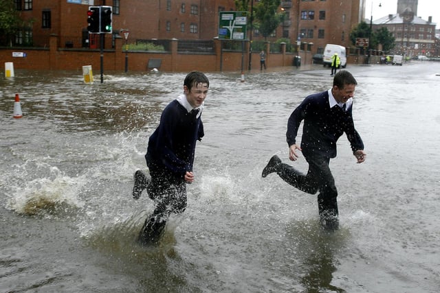 June 2007 and schoolchildren run through flood waters after the banks of the River Aire in Leeds city centre were broken by heavy rain fall.