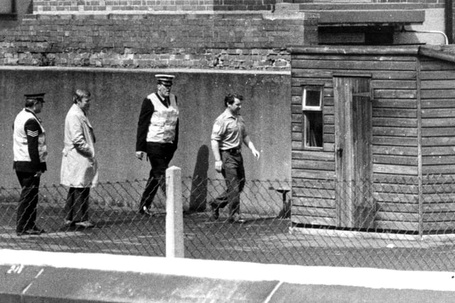 Three policemen an army bomb disposal expert going to examine the bomb behind a shed at Queen Street First School, Normanton, in 1980 - It was taken into the school by a pupil for a project, but it was later found to be a live smoke bomb
