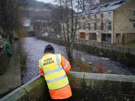 Volunteer flood warden Keith Crabtree MBE checks the river levels of Hebden Beck as rain and recent melting snow begin to raise river levels