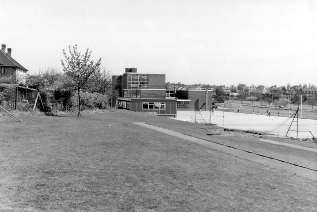 The school yard with the jumping-pit running diagonally across the foreground and the vandalised tennis court on the right. The prefab building in the centre is the Art Block.