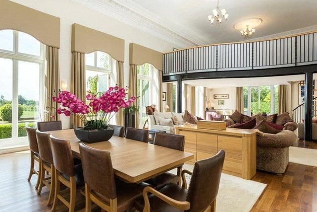 The open plan dining room features American oak flooring, a marble fireplace and living flame gas fire, and tall picture windows including two sets of French doors which open into the garden.