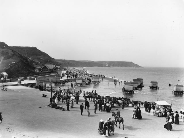 circa 1913: Day-trippers on the North Beach at Scarborough where they are offered rides, bathing machines and a souvenir stall, as well as the beach itself.