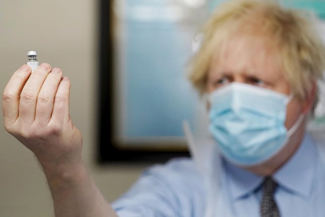 Prime Minister Boris Johnson holds a bottle of the Pfizer BioNTech vaccine as he visits a COVID-19 vaccination centre in Batley
