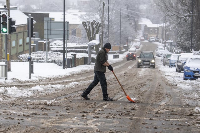 A local resident clears Rodley Lane by the Outer Ring Road after fresh heavy snowfall arrived overnight in west Leeds.