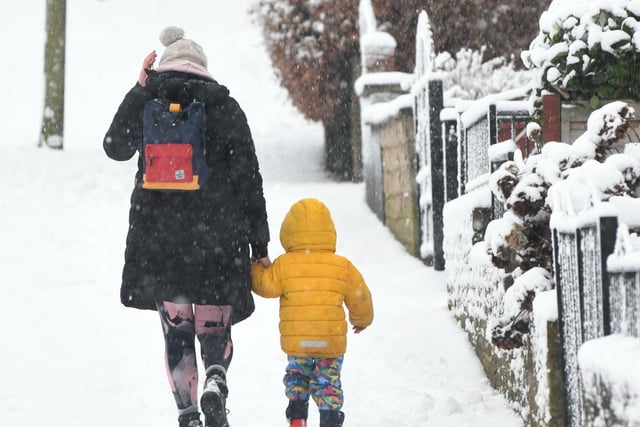 A mum and toddler walk through the snow in Cross Gates, east Leeds.