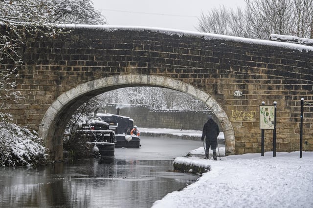 A walker on the towpath by Fallswood Marina, Bramley on the Leeds Liverpool canal after fresh heavy snowfall arrived overnight in West Leeds.