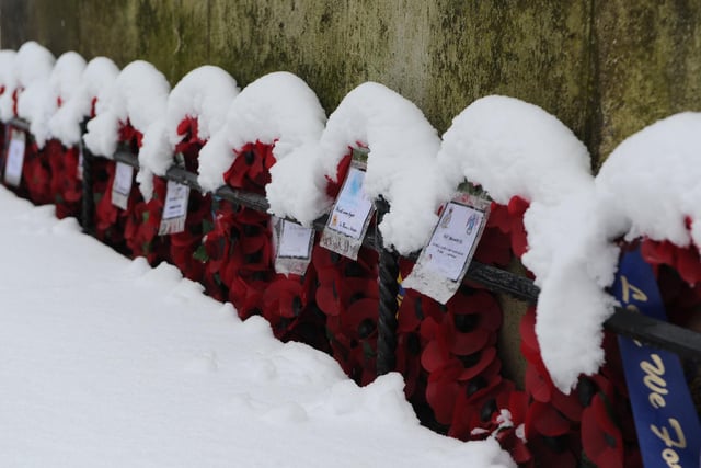 Wreaths at the War Memorial covered in snow.