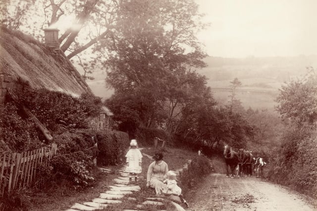 A woman and two children playing by the roadside in Whitby, circa 1880.