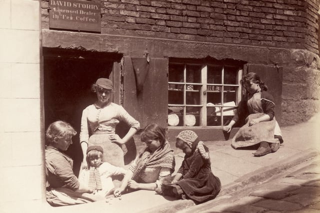circa 1880: Children playing outside a shop at the foot of the church steps in Whitby.